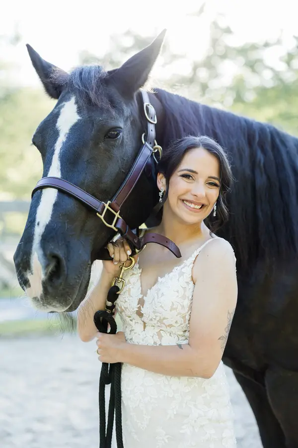A bride smiling beside one of the farm's horses